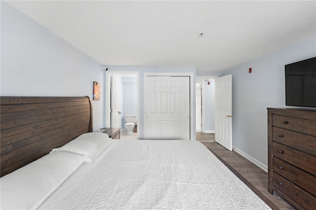 bedroom featuring wood finished floors, a closet, baseboards, and connected bathroom
