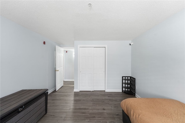 bedroom with dark wood-style flooring, a closet, baseboards, and a textured ceiling