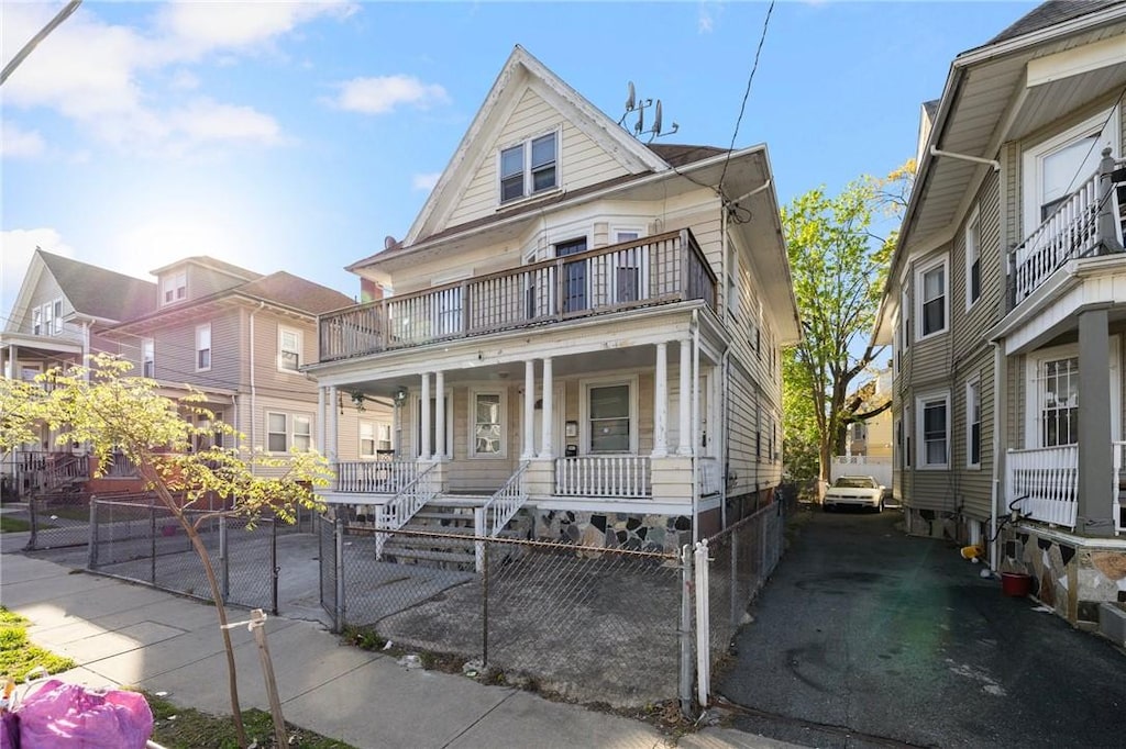 108 Lenox Ave, Providence, RI 02907 - view of front of house featuring covered porch, a balcony, and a fenced front yard
