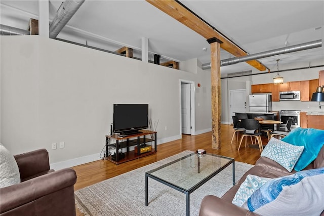 living room featuring wood finished floors, baseboards, and beam ceiling