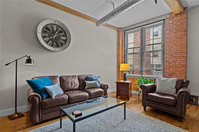 living room with baseboards, wood finished floors, beam ceiling, and brick wall