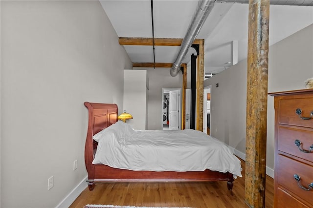 bedroom with baseboards, wood finished floors, and a spacious closet
