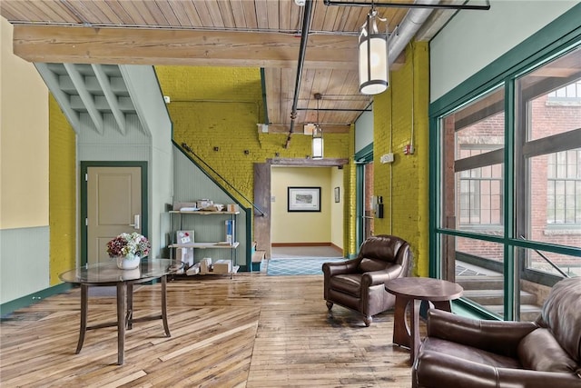 community lobby with beam ceiling, wooden ceiling, a towering ceiling, and brick wall