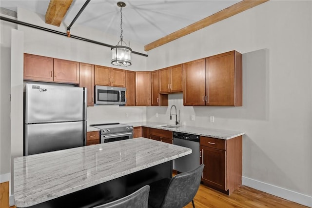 kitchen featuring stainless steel appliances, a sink, baseboards, light wood finished floors, and light stone countertops