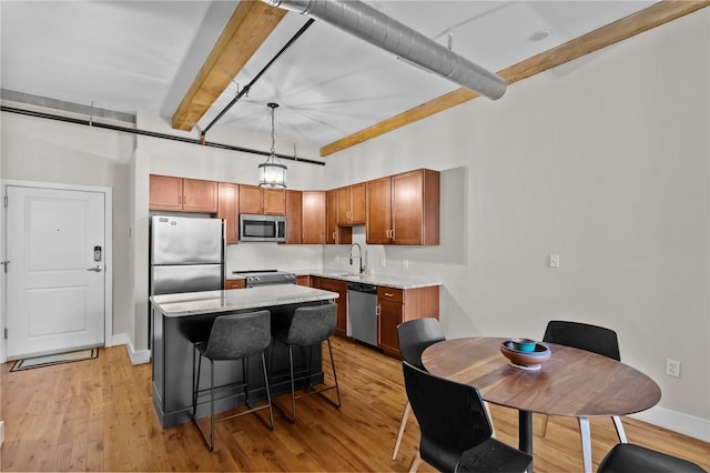 kitchen with stainless steel appliances, beamed ceiling, light wood finished floors, and a kitchen island