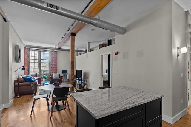 kitchen with dark cabinets, light wood-type flooring, open floor plan, baseboards, and light stone countertops