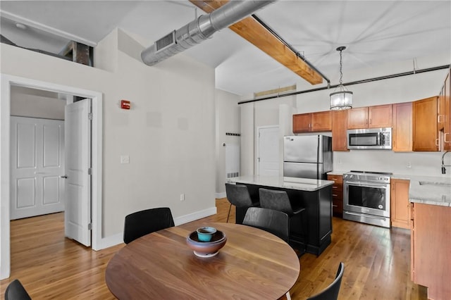 dining space featuring light wood finished floors, beamed ceiling, and baseboards