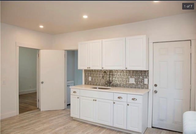 87 Oakland Ave, Providence, RI 02908 - kitchen featuring a sink, light countertops, white cabinets, decorative backsplash, and light wood-style floors