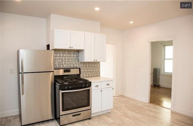 87 Oakland Ave, Providence, RI 02908 - kitchen featuring appliances with stainless steel finishes, radiator heating unit, white cabinetry, tasteful backsplash, and light countertops