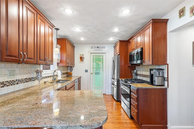 50 Harold St, East Providence, RI 02915 - kitchen featuring appliances with stainless steel finishes, a sink, light stone countertops, a peninsula, and light wood-type flooring