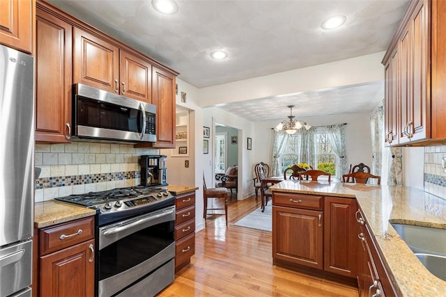 50 Harold St, East Providence, RI 02915 - kitchen featuring stainless steel appliances, a chandelier, brown cabinets, tasteful backsplash, and recessed lighting
