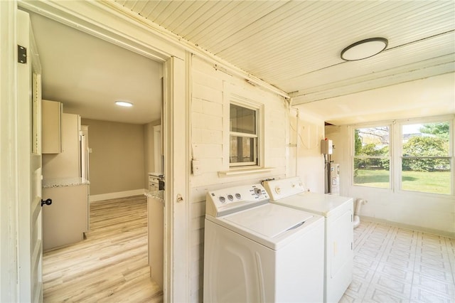 clothes washing area with washing machine and dryer, light flooring, water heater, and baseboards