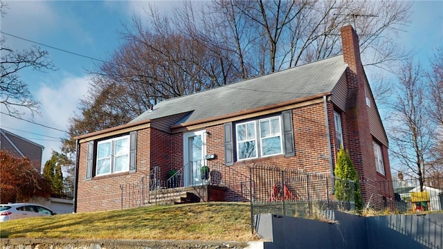 bungalow-style home featuring brick siding and a chimney