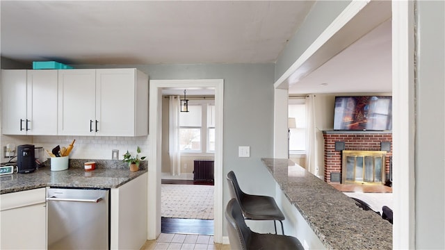 kitchen with dark stone counters, tasteful backsplash, white cabinetry, and a fireplace