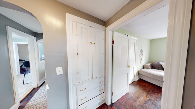 hall featuring arched walkways and dark wood finished floors