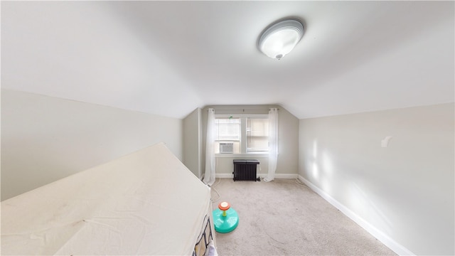 unfurnished bedroom featuring light colored carpet, vaulted ceiling, and baseboards