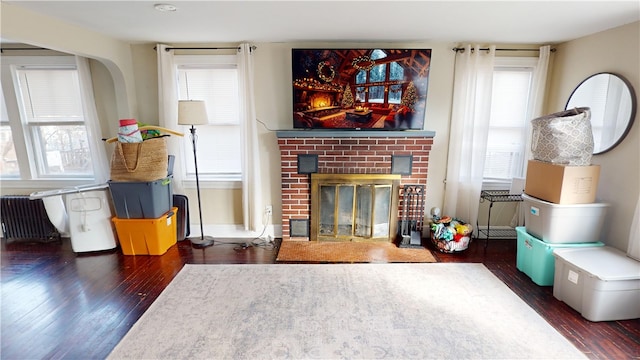 living area featuring wood finished floors, a brick fireplace, and baseboards