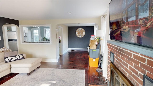 foyer entrance with arched walkways, wood finished floors, baseboards, and a fireplace