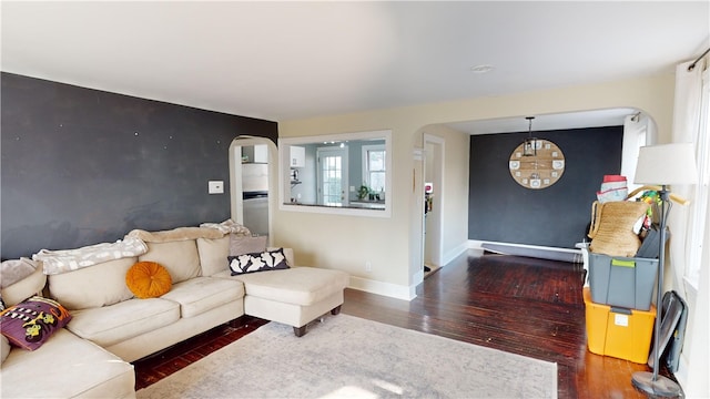 living area featuring arched walkways, wood finished floors, and baseboards