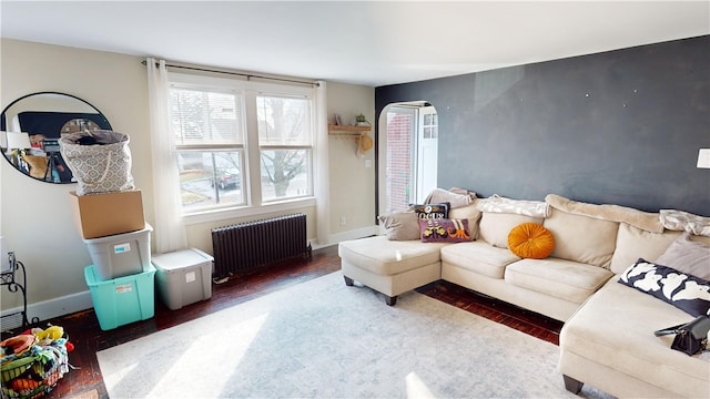 living room with radiator, wood finished floors, arched walkways, and baseboards