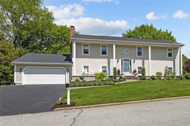 view of front of property with a chimney, driveway, an attached garage, and a front yard