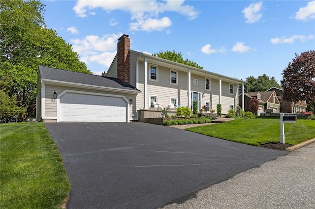 view of front of home with a chimney, asphalt driveway, a front yard, and an attached garage
