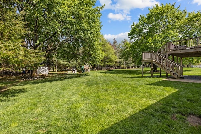 view of green lawn with stairway and a deck