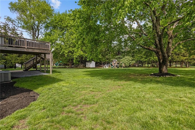 view of grassy yard with a playground, a storage shed, cooling unit, a deck, and stairway