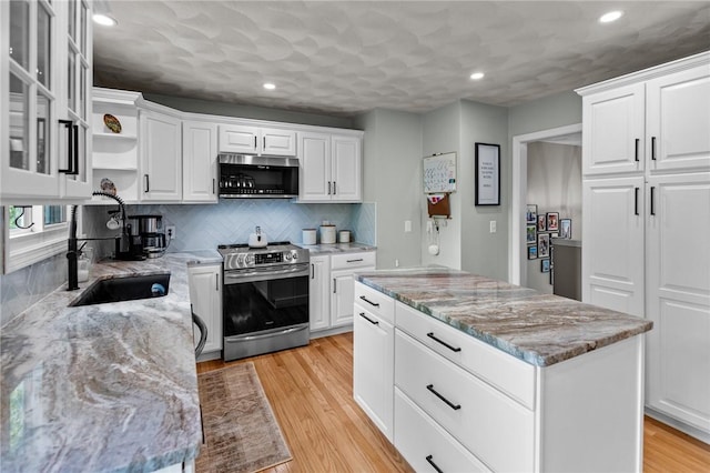 kitchen featuring appliances with stainless steel finishes, recessed lighting, a center island, white cabinets, and light stone countertops