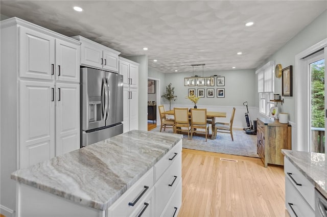 kitchen featuring stainless steel fridge with ice dispenser, recessed lighting, white cabinets, light wood-style floors, and light stone countertops