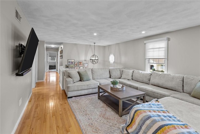living room featuring light wood-style flooring, baseboards, recessed lighting, and a chandelier