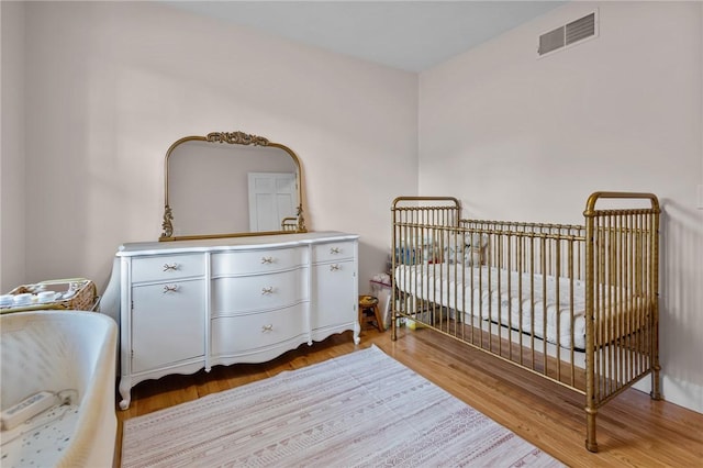 bedroom featuring light wood-style floors and a crib