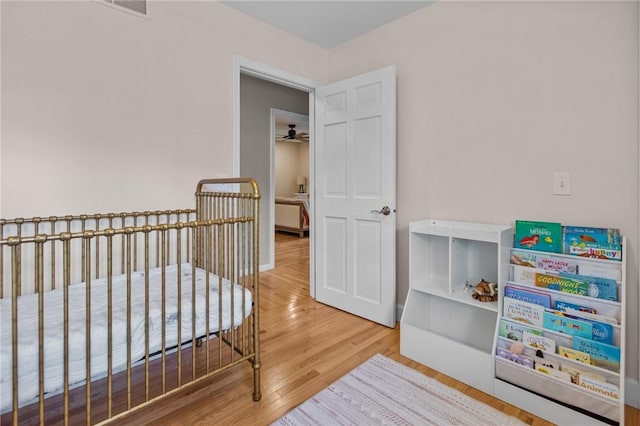 bedroom with wood finished floors and a nursery area