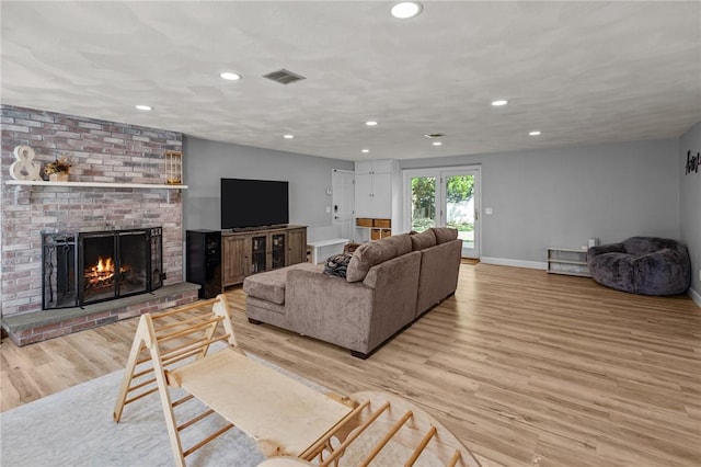 living room with light wood finished floors, baseboards, a brick fireplace, and recessed lighting