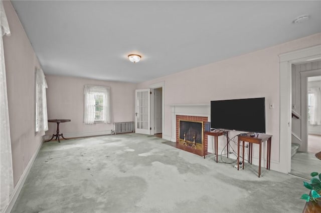 57 Sylvan Rd, East Providence, RI 02916 - unfurnished living room with radiator heating unit, a brick fireplace, baseboards, and stairway