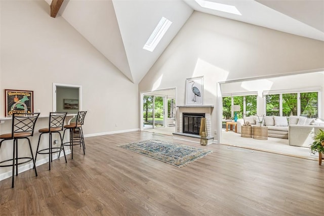 26 Bagy Wrinkle Cv, Warren, RI 02885 - living area featuring a skylight, high vaulted ceiling, wood finished floors, baseboards, and a brick fireplace