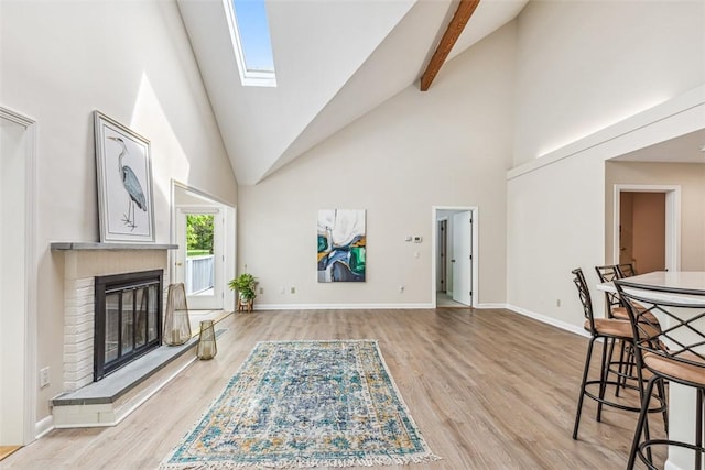 26 Bagy Wrinkle Cv, Warren, RI 02885 - living room with high vaulted ceiling, light wood-style flooring, a brick fireplace, a skylight, and baseboards