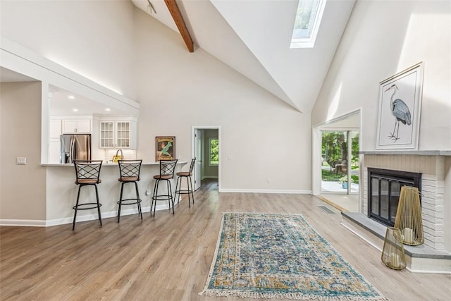 26 Bagy Wrinkle Cv, Warren, RI 02885 - living area with a skylight, high vaulted ceiling, a brick fireplace, light wood finished floors, and baseboards
