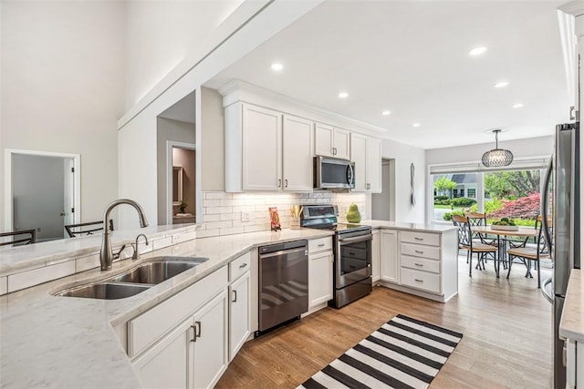 26 Bagy Wrinkle Cv, Warren, RI 02885 - kitchen with stainless steel appliances, a sink, a peninsula, decorative backsplash, and white cabinets
