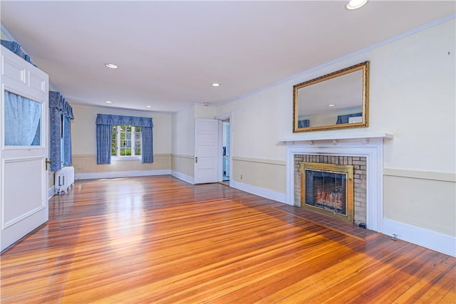 43 Standish Rd, Jamestown, RI 02835 - unfurnished living room with radiator, light wood-style flooring, a brick fireplace, ornamental molding, and recessed lighting