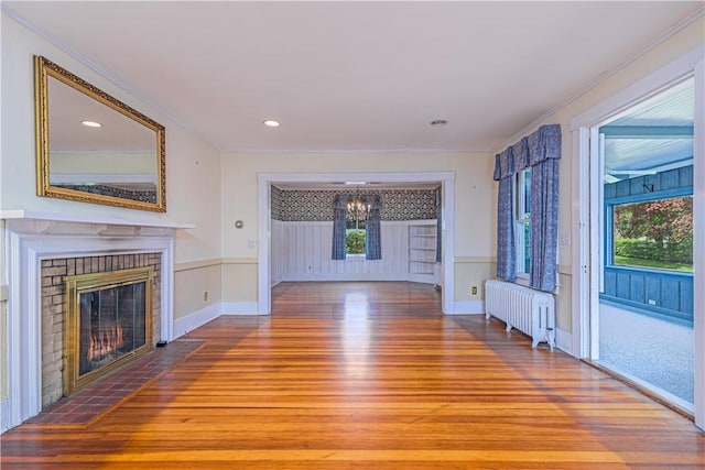 43 Standish Rd, Jamestown, RI 02835 - unfurnished living room featuring radiator, wood finished floors, a chandelier, a fireplace, and crown molding
