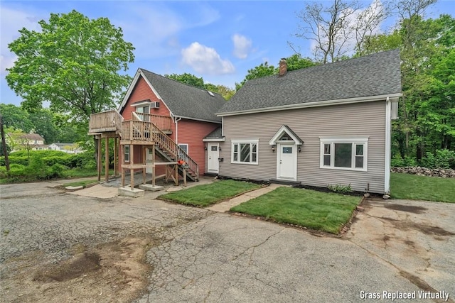 rear view of house with stairway, a chimney, a deck, and a lawn