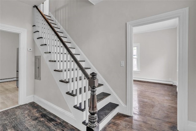 staircase with baseboard heating, wood finished floors, electric panel, and a baseboard radiator