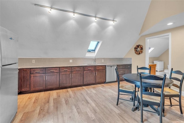 kitchen featuring appliances with stainless steel finishes, a skylight, track lighting, vaulted ceiling, and a sink