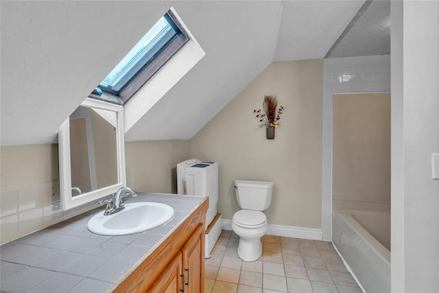 bathroom featuring a skylight, vaulted ceiling, toilet, tile patterned floors, and vanity