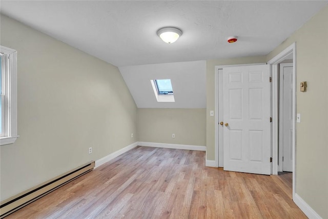 bonus room featuring baseboard heating, a skylight, light wood-style floors, baseboards, and lofted ceiling