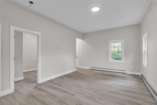 spare room with a baseboard heating unit, wood finished floors, and baseboards
