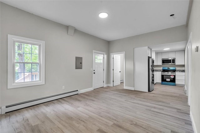 unfurnished living room with a baseboard heating unit, light wood-style floors, baseboards, and electric panel