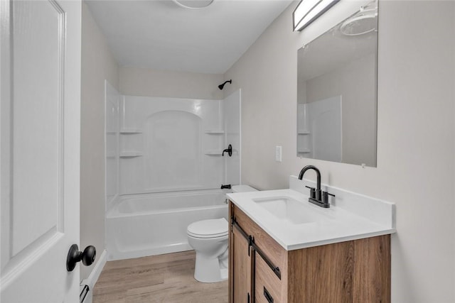 bathroom featuring wood finished floors, toilet, vanity, and bathtub / shower combination