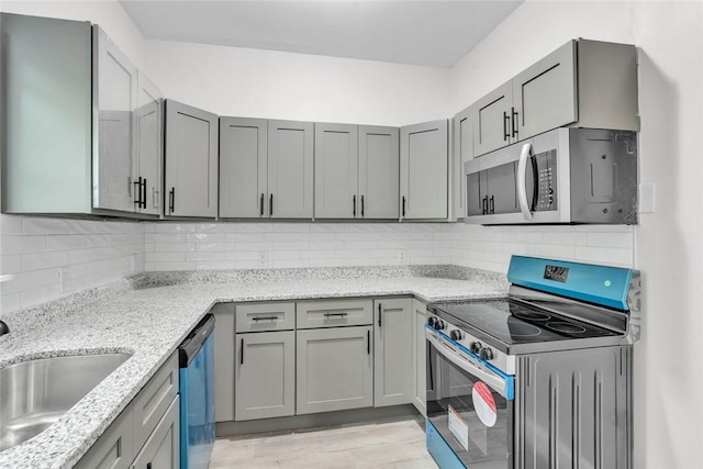 kitchen featuring appliances with stainless steel finishes, light stone counters, tasteful backsplash, and gray cabinets